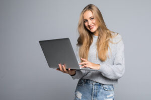 young-happy-smiling-woman-casual-clothes-holding-laptop-sending-email-her-best-friend-isolated-gray-background